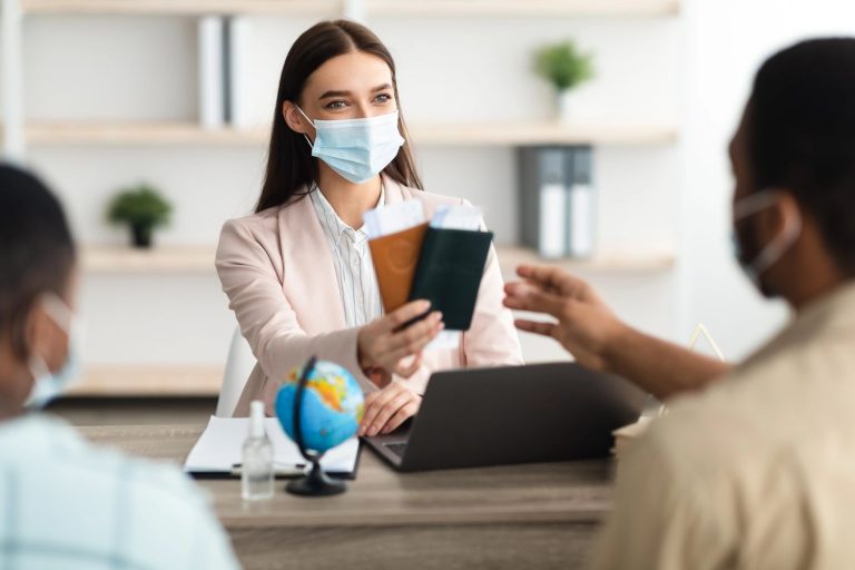 A professional handing over documents during an immigration medical physical in Houston, with a globe and laptop on the desk.