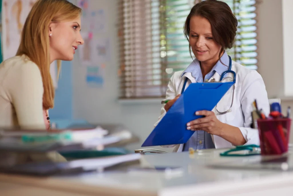 Patient consults with immigration doctor Houston reviewing medical clipboard in a well-equipped clinic office setting.