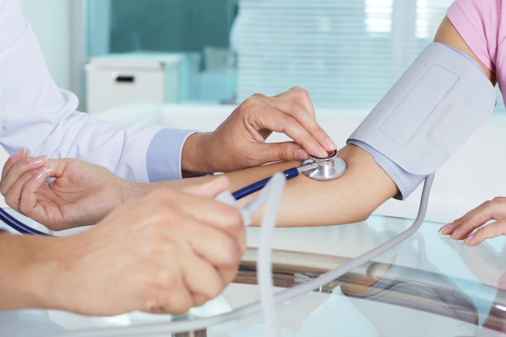 Medical professional checks vitals during cheapest immigration medical exam Houston in clean, clinical environment.