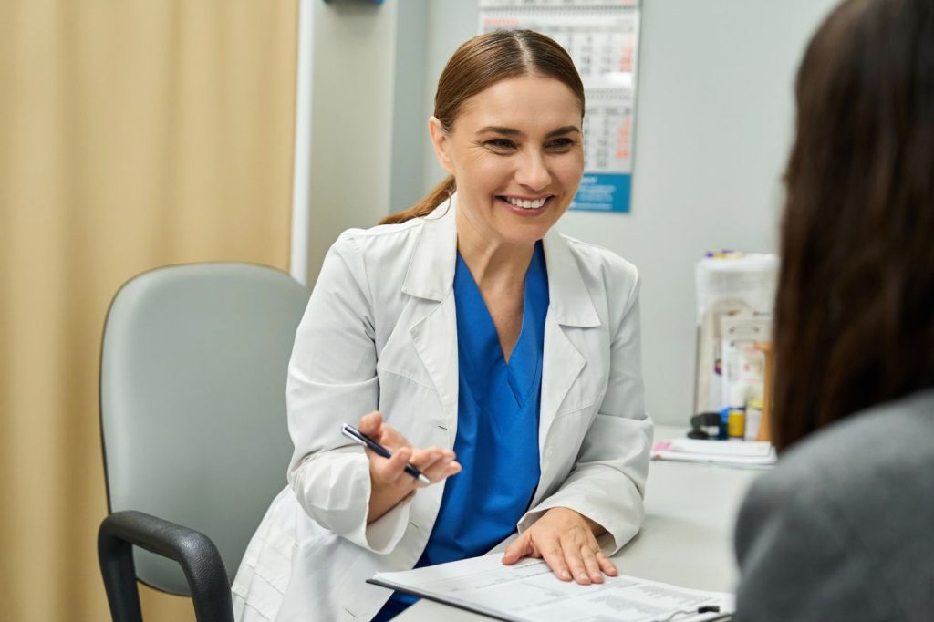 Smiling doctor explains procedure during cheapest immigration medical exam Houston in welcoming clinic consultation room.