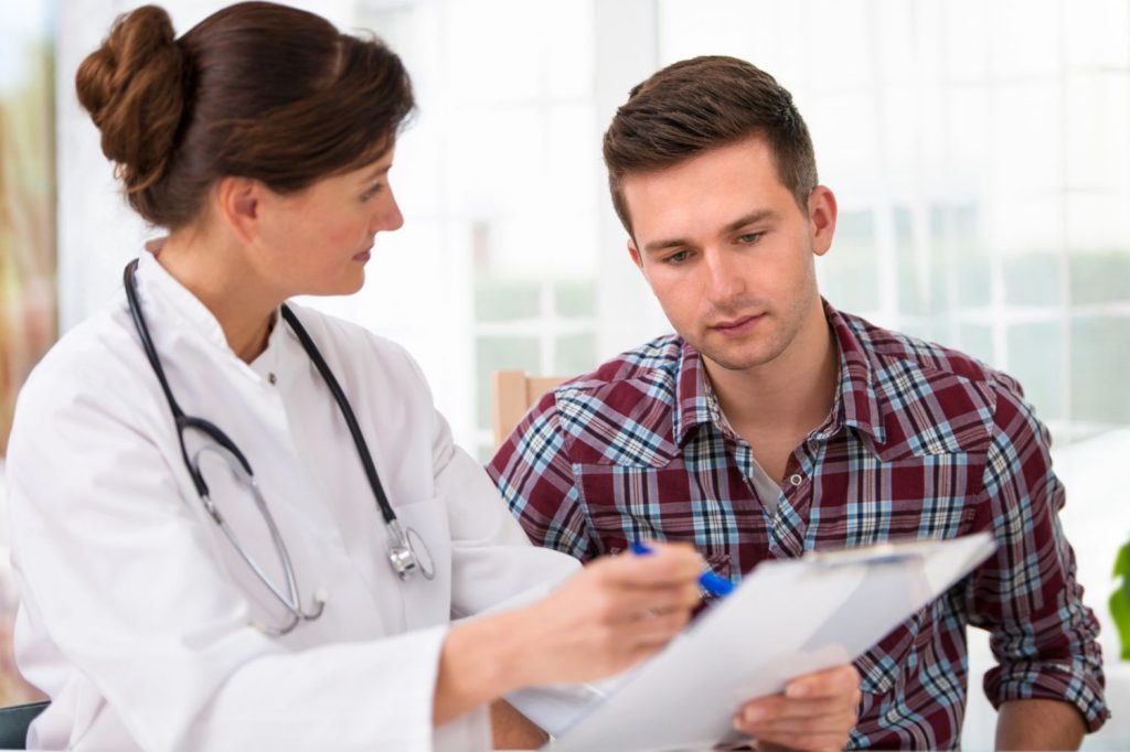 Immigration doctor Houston explains medical form to patient during exam consultation in bright, modern clinic setting.