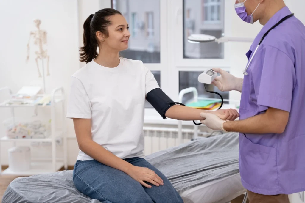 Doctor measuring blood pressure of female patient in clinic with skeleton chart for immigration medical exam Houston.