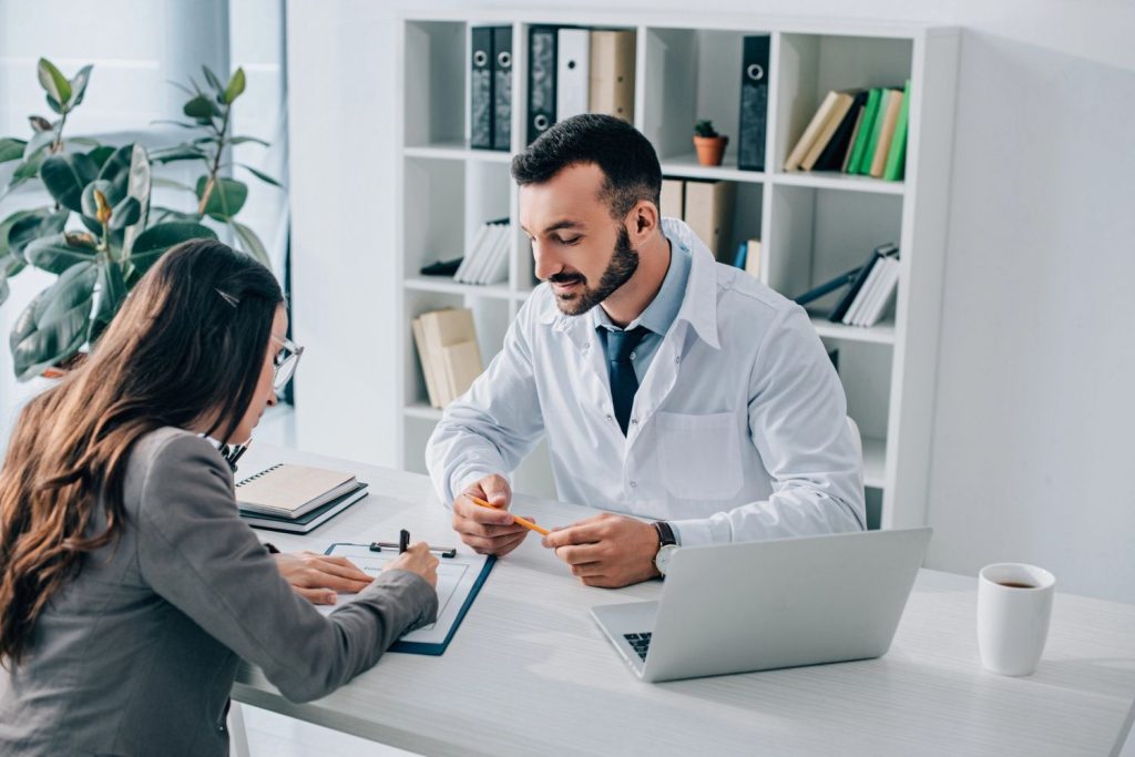 Doctor consults patient completing paperwork during USCIS immigration medical exam in professional Houston office