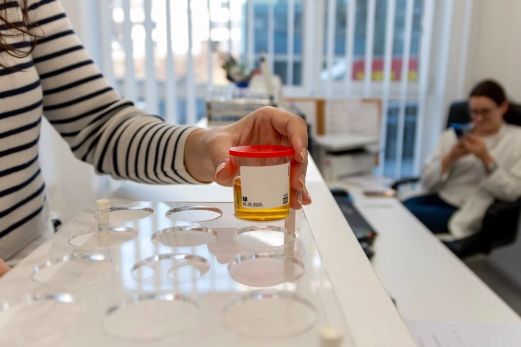 patient prepares sample for immigration doctor Houston exam using beaker and test tube in sterile lab setting.