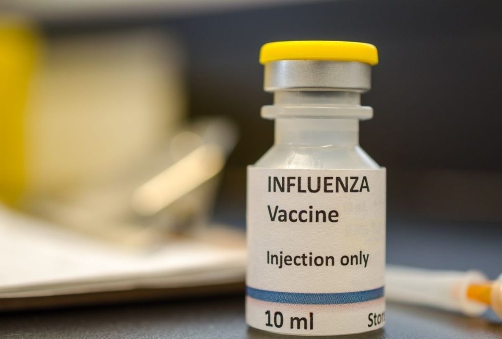 Close-up of influenza vaccine vial used in USCIS immigration medical physical exam at approved Houston healthcare facility.