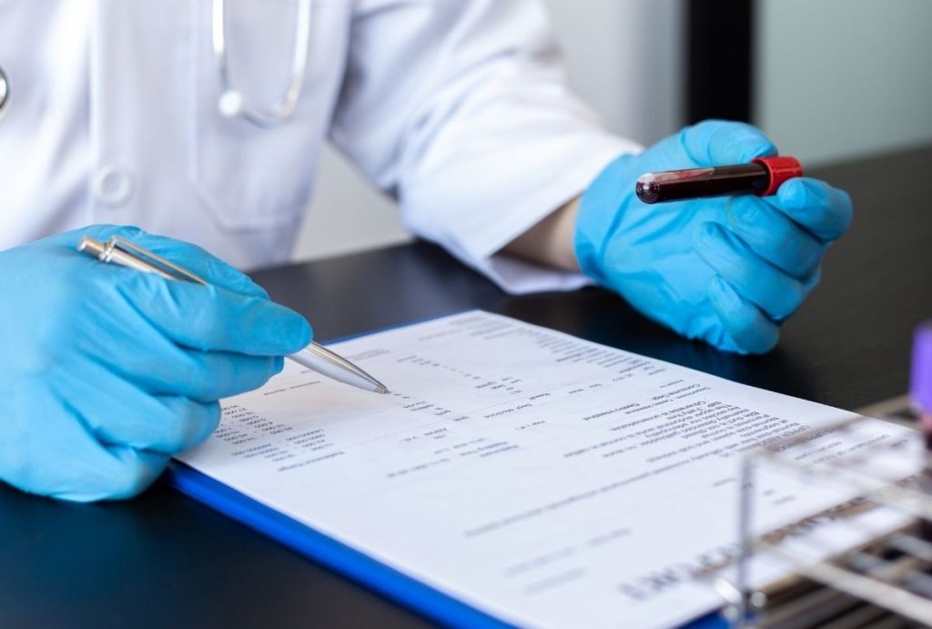 Doctor in gloves reviewing blood sample and lab report during immigration medical exam same day appointment Houston clinic.