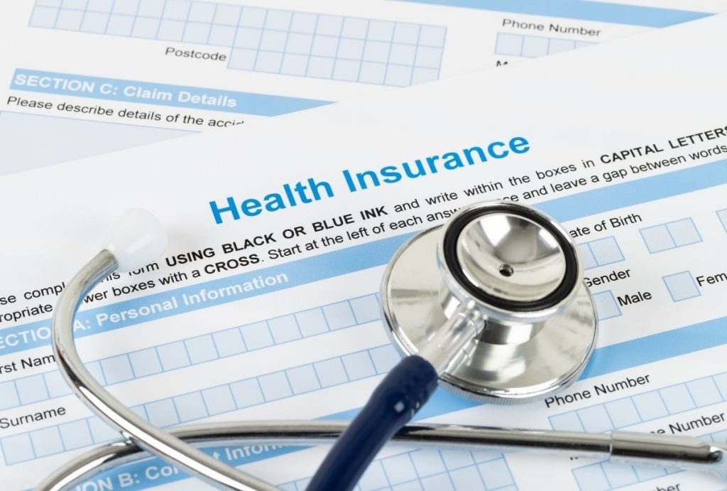 Health insurance paperwork and stethoscope prepared for USCIS immigration medical physical at certified Houston clinic