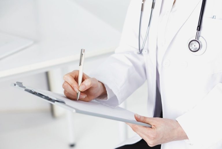 Healthcare professional completing USCIS immigration medical physical documentation at Houston clinic with stethoscope.