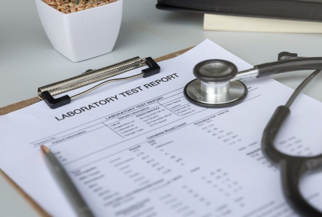 Lab test results reviewed for cheapest immigration medical exam Houston with stethoscope and clipboard on desk.