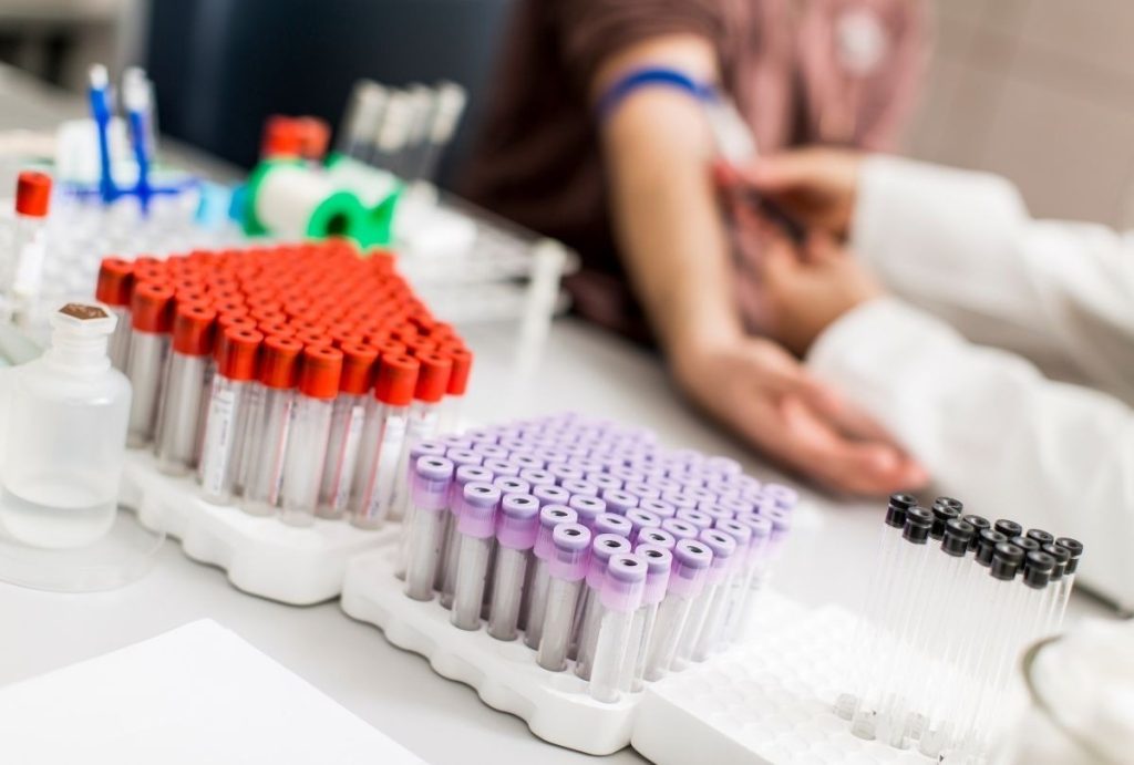 Medical staff drawing blood with organized test tubes during USCIS immigration medical physical at certified clinic
