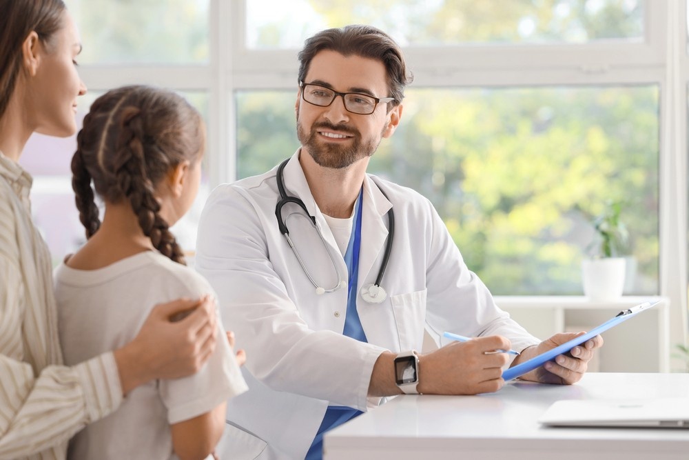 Mother and child discussing cheapest immigration medical exam Houston options with smiling family medicine doctor.