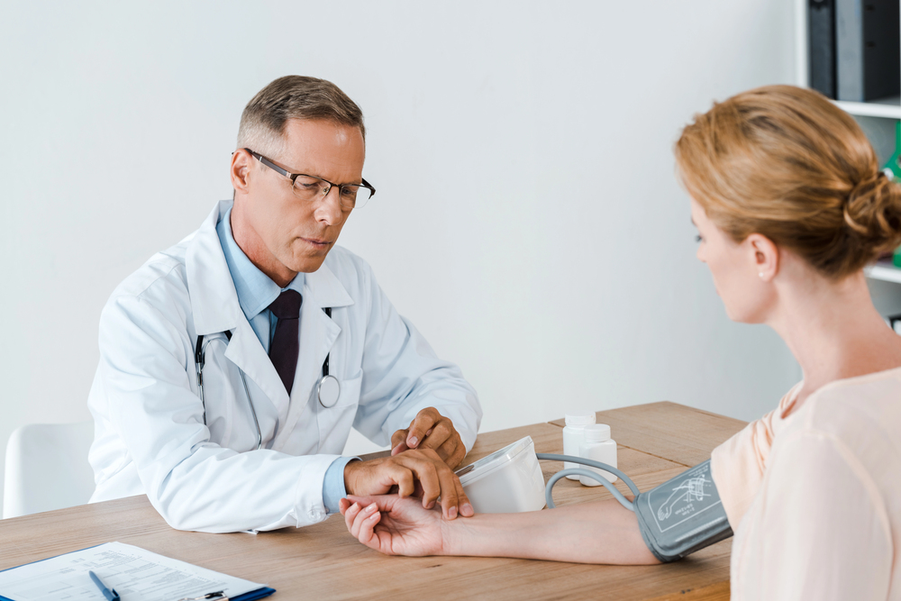 Immigration exam clinic open now Houston doctor checking patient’s blood pressure and pulse during immigration medical exam