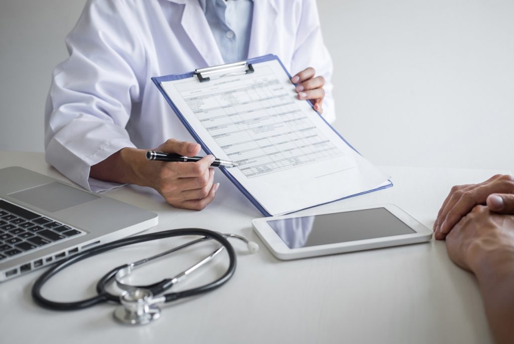 Civil surgeon reviewing Form I-693 paperwork for an immigration medical exam Houston in a clinic setting for applicants.