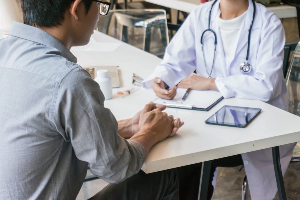 Healthcare provider and patient during an immigration medical physical Houston consultation at a medical office desk.