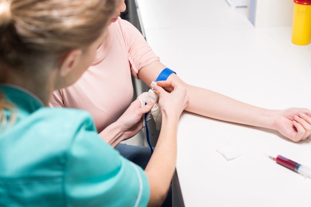 Immigration exam clinic open now Houston nurse drawing patient’s blood for medical tests in clean, professional lab setting
