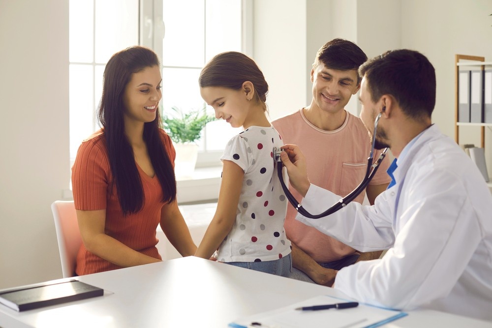 Parents at cheapest immigration medical exam Houston as doctor checks young daughter during pediatric health visit.