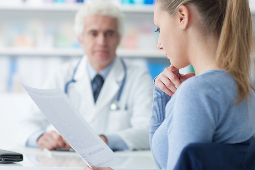 Woman reviewing medical report with i 693 medical exam doctor Houston during detailed immigration health consultation in clinic.