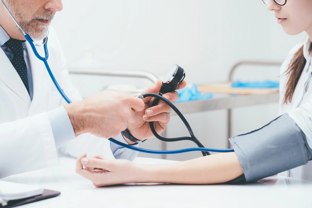 Doctor checking blood pressure during cheapest immigration medical exam Houston, professional healthcare service for visa applicants in modern clinic.