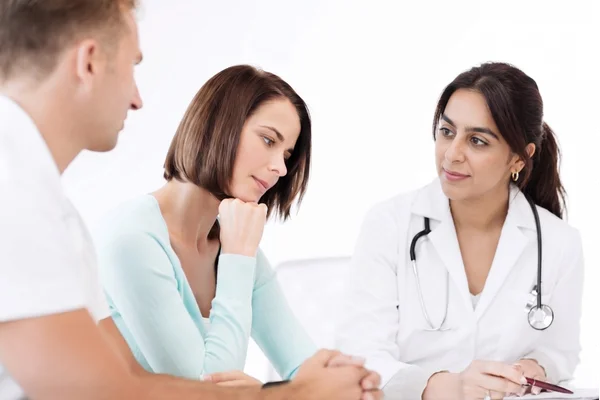 An immigration doctor Houston clinic consultation with a blonde female doctor speaking to a couple sitting at a desk.