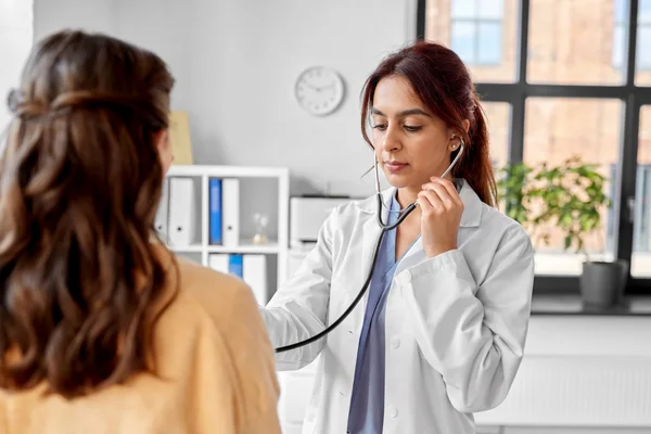 A female doctor checks a patient's lungs with a stethoscope at our immigration exam clinic open now Houston.