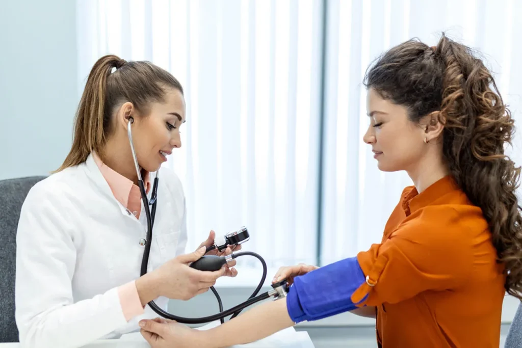 A female doctor takes blood pressure measurements on a patient at our immigration exam clinic open now Houston.