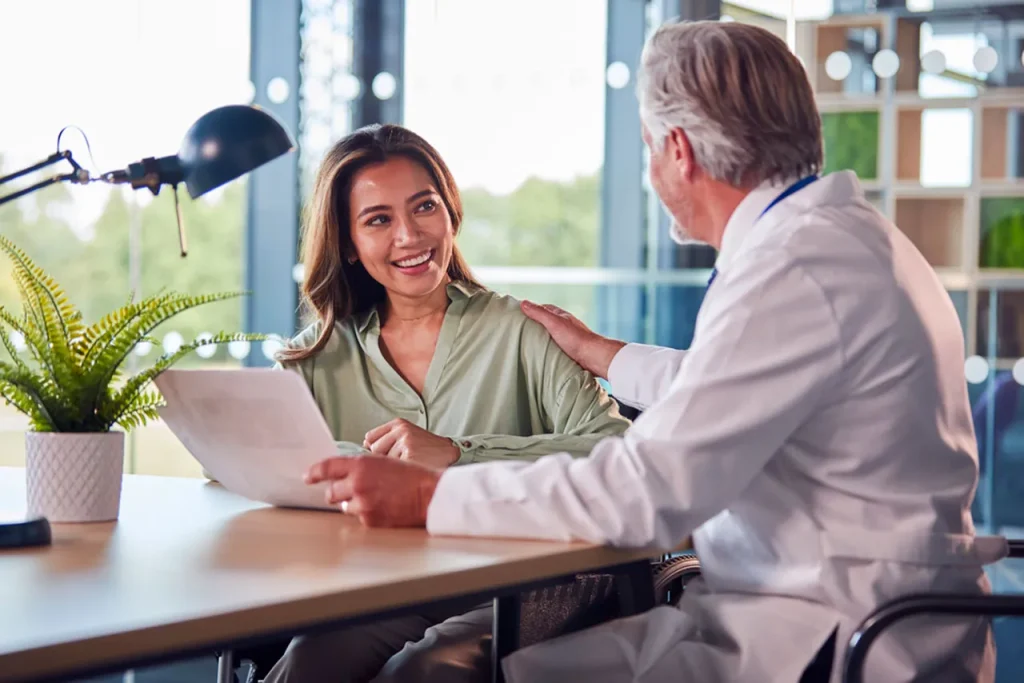 A smiling woman receives positive results during her final USCIS immigration medical exam consultation with a certified doctor.