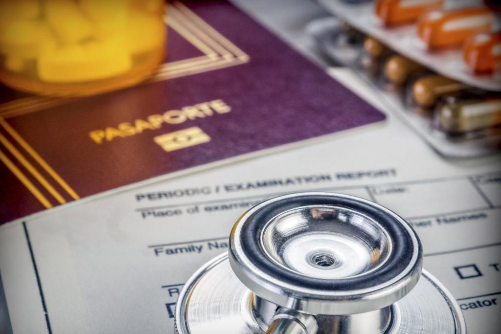 Medical exam paperwork for Form I-693 on a desk with a passport, pills, and help from a USCIS approved doctor Houston. 