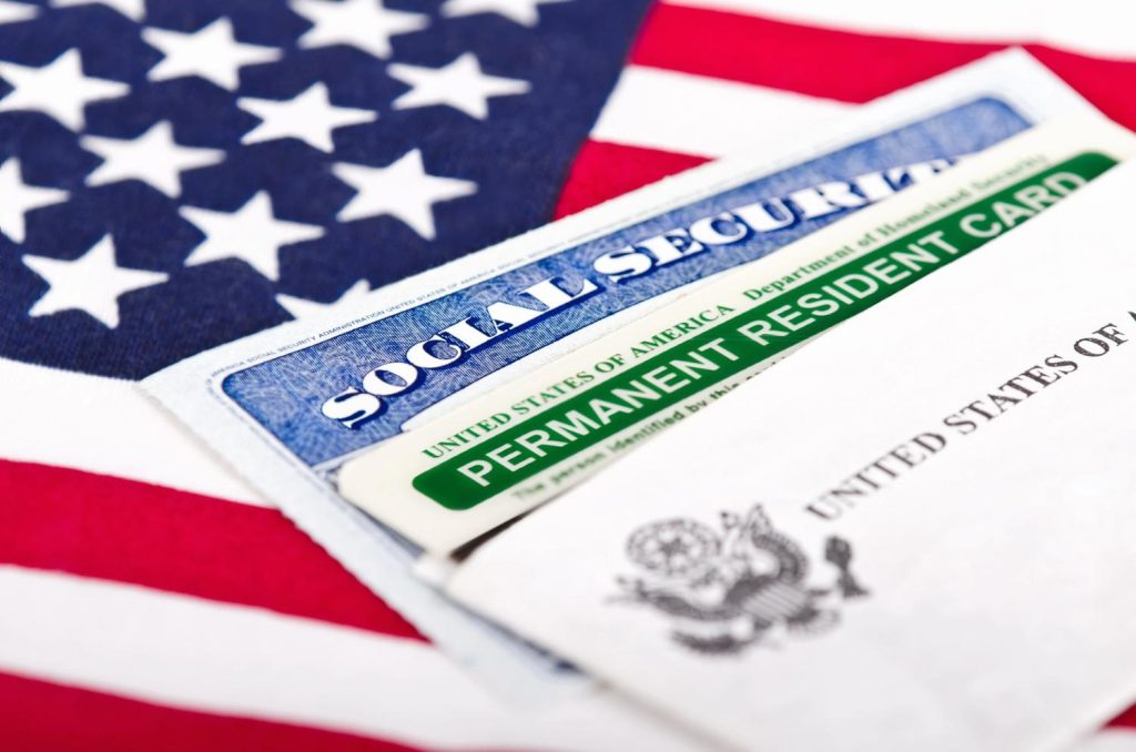 Permanent Resident Card and Social Security card on a US flag, ready for a USCIS civil surgeon Houston medical review. 